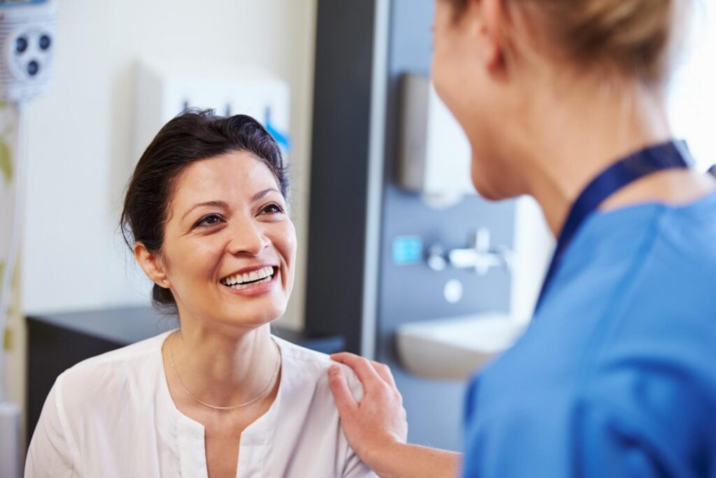 Female Patient Being Reassured By Doctor Hospital Room