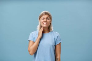 Woman holding her jaw in pain.